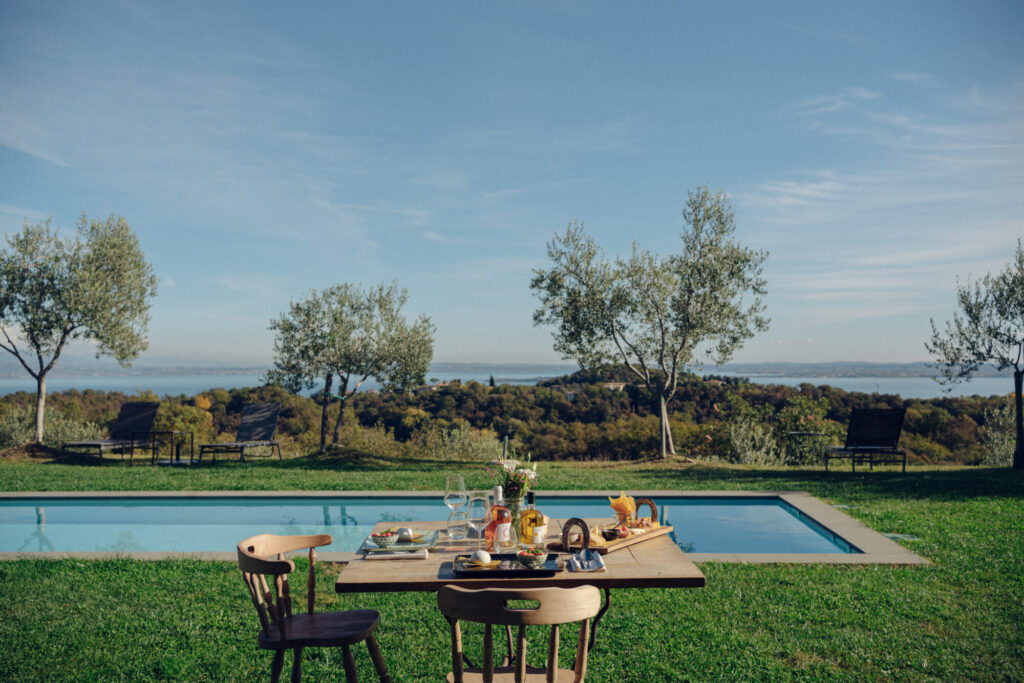 Tavolo da pranzo all'aperto vicino a una piscina con una vista panoramica su un paesaggio naturale.