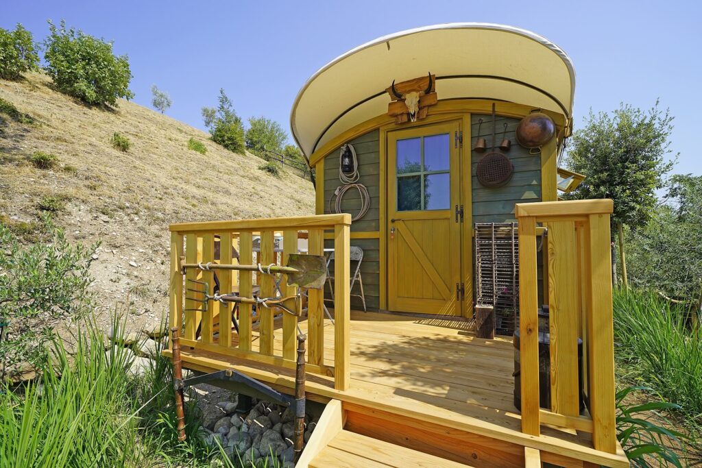Caravan rustica in legno situata in un ambiente naturale con vegetazione circostante.