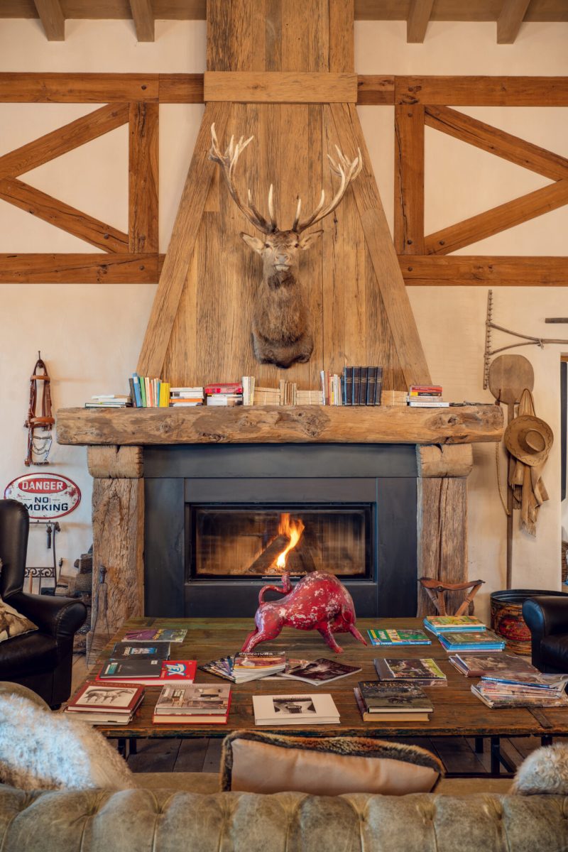 Camino rustico in legno con decorazioni e libri su mensola in soggiorno accogliente.